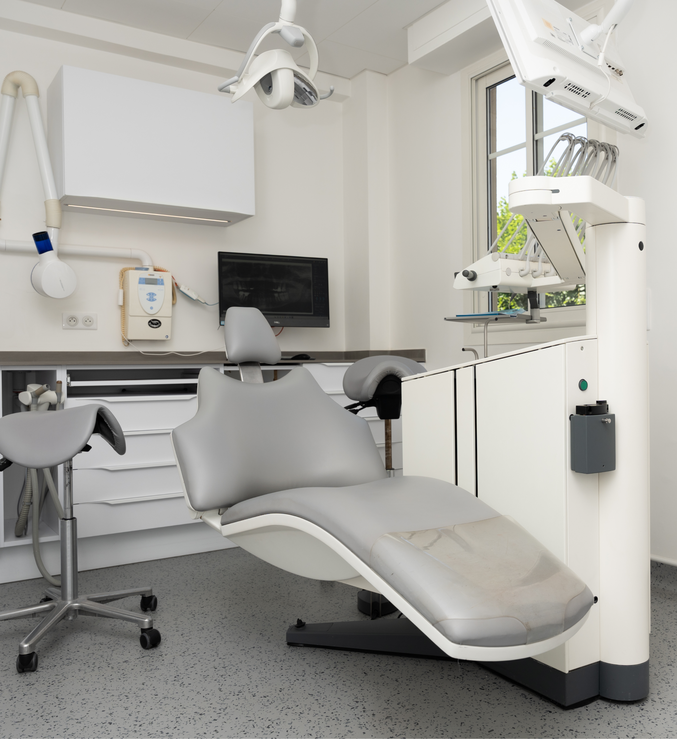 Cabinet de soins équipé, fauteuil gris et éclairage scialytique